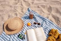 brown glass bottle beside white book on blue and white textile (Foto: S'well / Unsplash)