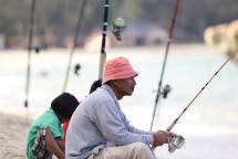 Man and child enjoy fishing at the beach with rods under a day sky. (Foto: Pok Rie / Pexels)
