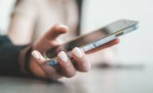 A person holding a smartphone with a marble pattern case in a bright room (Foto: Jae Park / Unsplash)