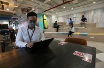 Sejumlah Karyawan Bank DBS Indonesia Duduk Sesuai dengan Penanda Jarak Saat Bekerja di Area Kantor DBS Tower