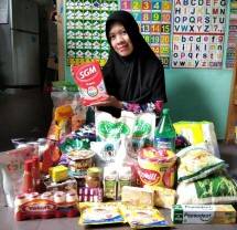 Ibu Kantin Sekolah Generasi Maju Memperlihatkan Belanjaan Kebutuhan Gizi dan Nutrisi Hasil dari Menukarkan e-voucher